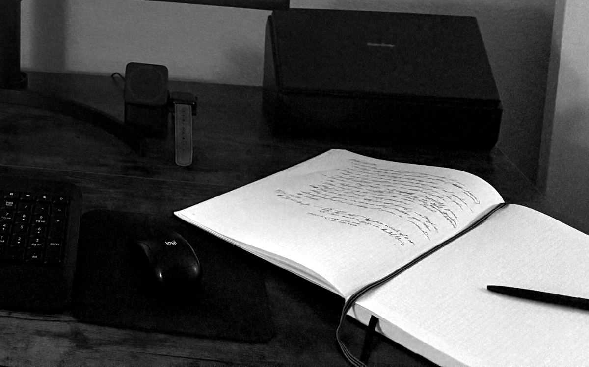 An open notebook of handwritten notes on the studio desk, beside a keyboard.